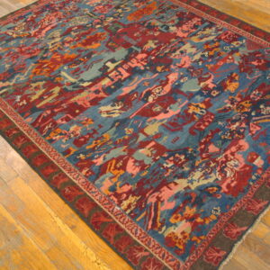 Angled view of a vibrant rug with abstract red, blue, and coral patterns on wood flooring.