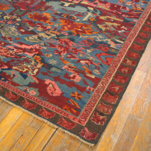 A colorful geometric rug with blue and deep red abstract patterns rests on light wood plank flooring.
