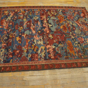 Low-pile rug with complex abstract patterns in blues, reds, and peach lying on rustic hardwood planks.