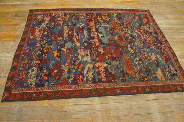 Low-pile rug with complex abstract patterns in blues, reds, and peach lying on rustic hardwood planks.