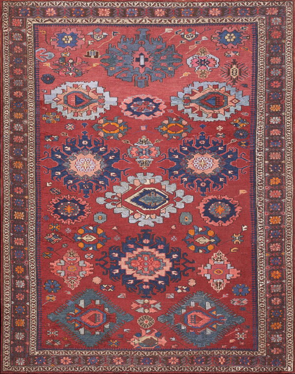 A rust-colored rug features stylized tribal geometric patterns in navy blue, slate gray, and pink tones.