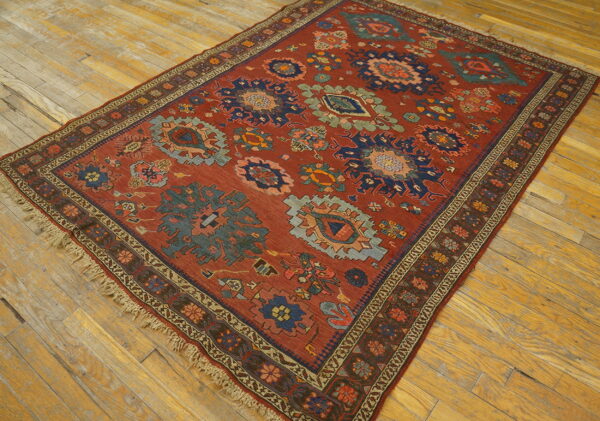 Geometric rust-toned rug featuring navy and sage medallions on a distressed wood floor.