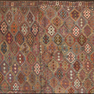 A low-pile textile featuring a rich geometric mosaic of nested diamonds in red, blue, gold, and earth tones.