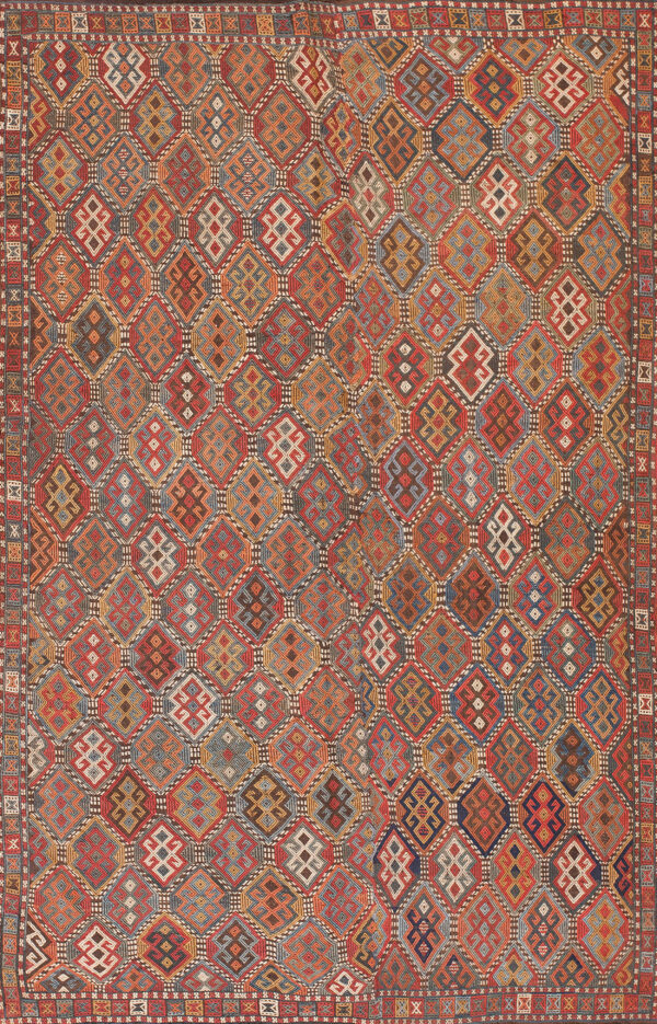 A low-pile textile featuring a rich geometric mosaic of nested diamonds in red, blue, gold, and earth tones.