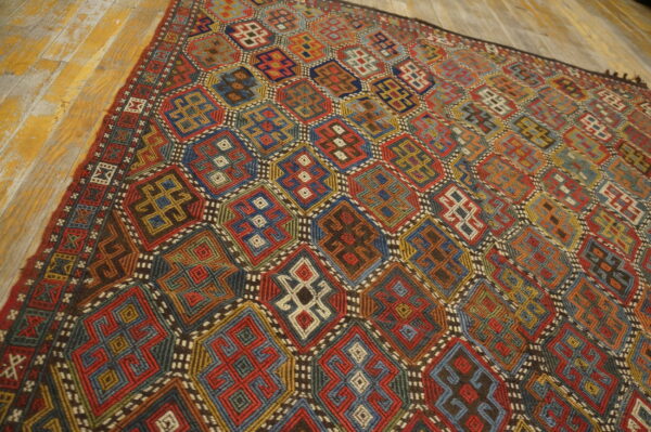 Vibrant geometric rug featuring complex octagonal patterns in red, blue, gold, and green on distressed wood.