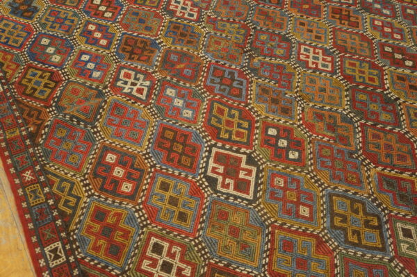 Low-pile rug with a complex geometric grid pattern in vibrant shades of red, blue, yellow, and green.