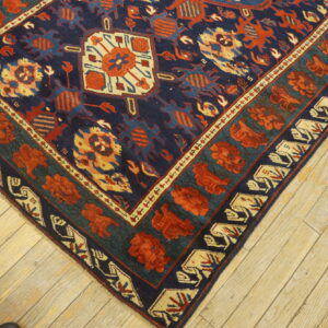 A high-pile rug with a navy, rust, teal, and cream geometric pattern lies on light wood floors.