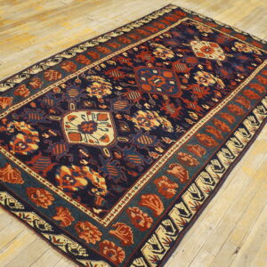 Navy, rust, and beige patterned rug with a geometric medallion motif on light colored wooden plank flooring.
