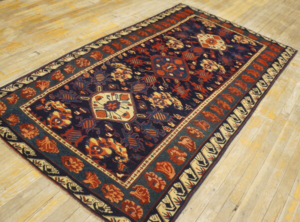 Navy, rust, and beige patterned rug with a geometric medallion motif on light colored wooden plank flooring.