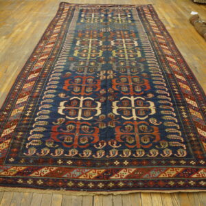 Dark blue runner rug featuring repeating red and beige geometric motifs on a wide plank wood floor.