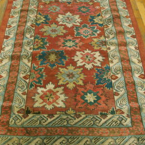 Red and teal traditional runner rug with star patterns on a golden plank wood floor.