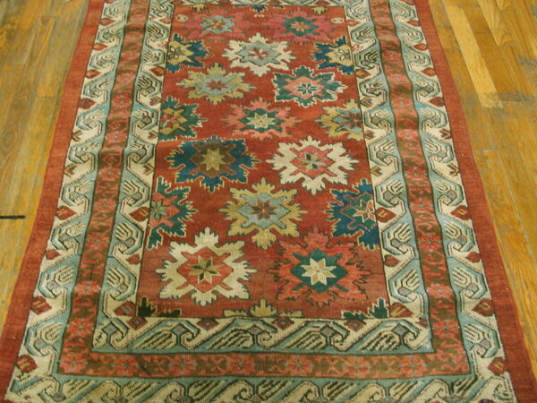 Red and teal traditional runner rug with star patterns on a golden plank wood floor.