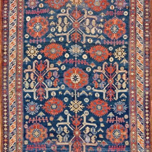 Deep indigo rug featuring repeating geometric medallions and symbols in rust, cream, and light blue.