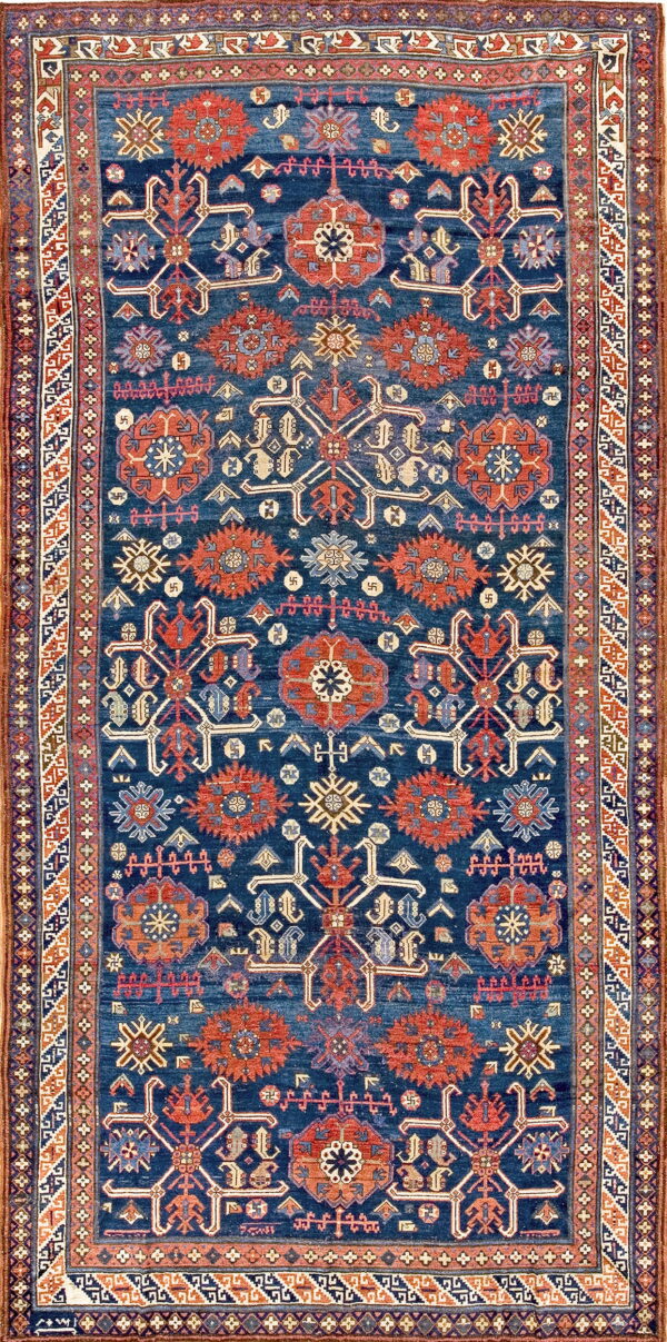 Deep indigo rug featuring repeating geometric medallions and symbols in rust, cream, and light blue.