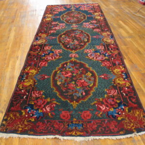 Runner rug featuring red, teal, gold, and blue floral medallions, lying on light wood flooring.
