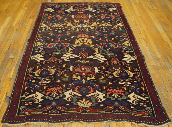Dark blue rug with multi-colored geometric and stylized patterns displayed on honey-toned wood floors.