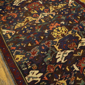 Short pile rug with stylized red, yellow, and cream figures on a dark blue field over light wood floors.