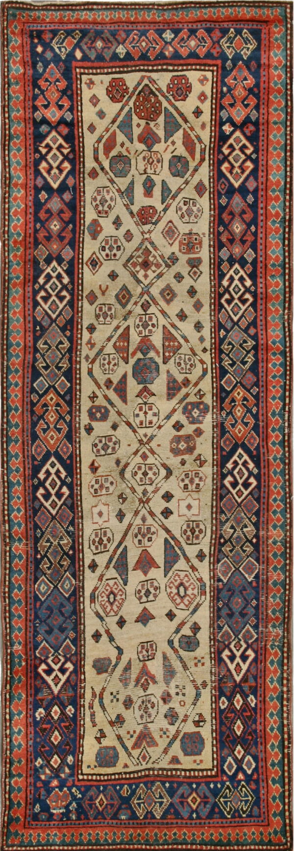 Runner rug featuring a cream field with geometric red and blue shapes enclosed by a dark blue patterned border.