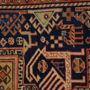 Detailed view of a dense, low-pile geometric pattern using contrasting navy blue, red, and tan colors.