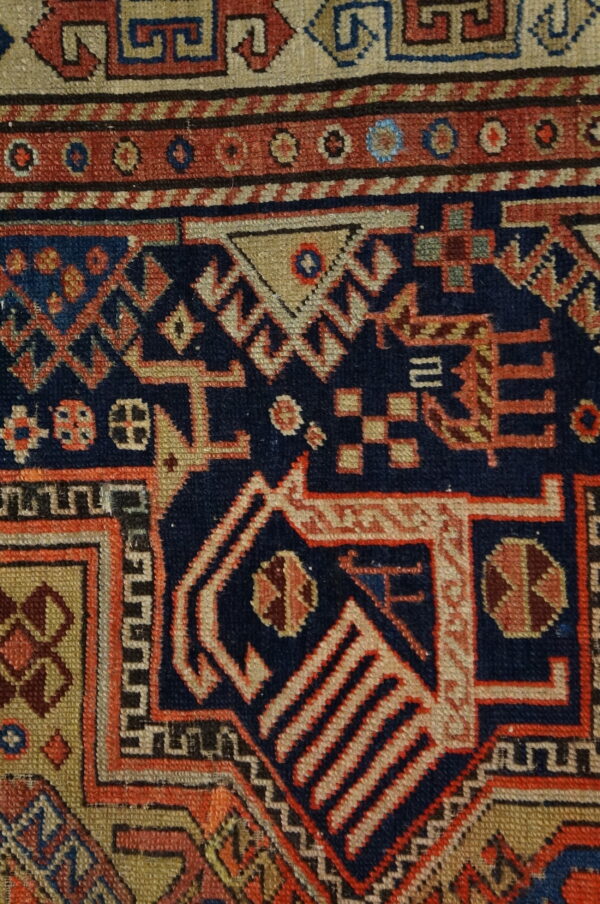 Detailed view of a dense, low-pile geometric pattern using contrasting navy blue, red, and tan colors.