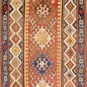 A low-pile geometric rug featuring a rust red central field and multi-layered cream, blue, and yellow borders.