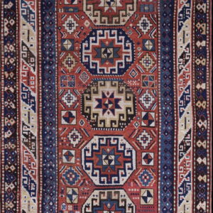 Low-pile rug with a detailed geometric pattern in red, navy blue, cream, and brown.