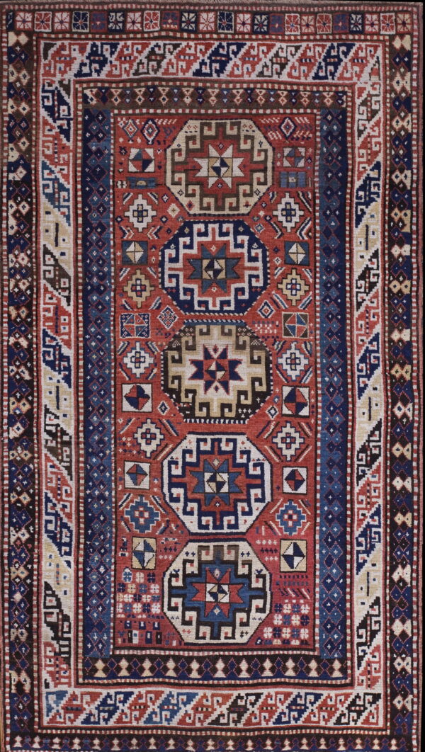 Low-pile rug with a detailed geometric pattern in red, navy blue, cream, and brown.