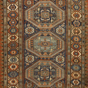 Intricate geometric rug displaying octagonal medallions, stylized animals, and wide borders in deep blue, rust, and cream.