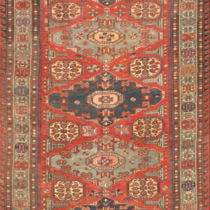 Red runner rug with navy and light blue geometric medallions and elaborate traditional borders.