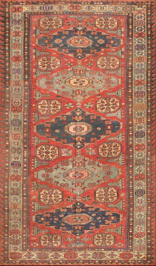 Red runner rug with navy and light blue geometric medallions and elaborate traditional borders.