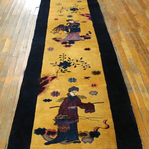 Long, black-bordered runner rug with a golden field displaying colorful traditional figures on hardwood.