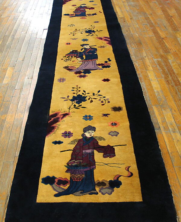 Long, black-bordered runner rug with a golden field displaying colorful traditional figures on hardwood.