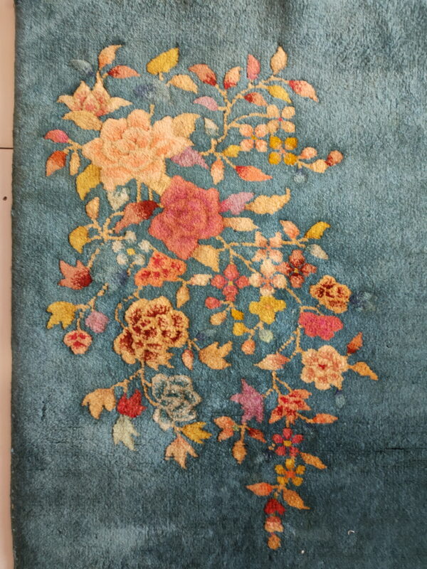 Muted teal rug featuring a dense, medium-pile design of cascading pink, peach, and yellow flowers.