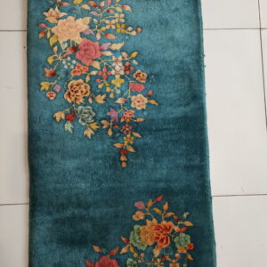 Teal runner rug featuring an asymmetrical floral pattern in pink, yellow, and red on white tile flooring.