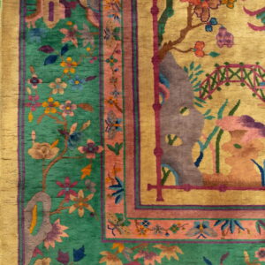 Detailed view of a gold and emerald green rug with multicolored botanical patterns and wide borders.