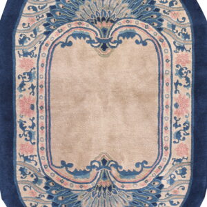 Ornamental oval rug in navy blue, beige, and pink, featuring large fan-like floral patterns.