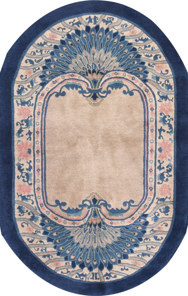 Ornamental oval rug in navy blue, beige, and pink, featuring large fan-like floral patterns.