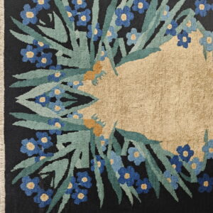 Dark floral rug featuring a dense blue and green border surrounding a large, plain tan central field.