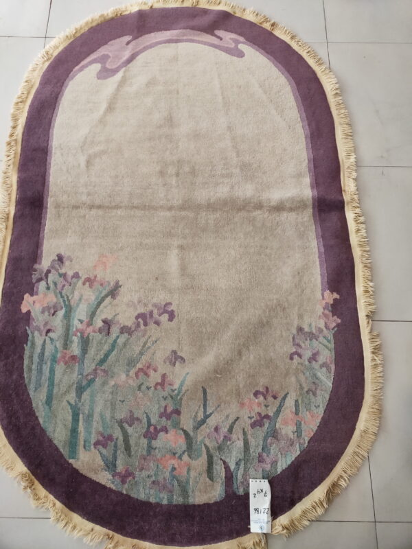 Light beige oval rug featuring a dark purple border and a multicolored botanical pattern at the bottom.