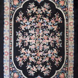 Black rug with a central multi-colored flowering tree pattern inside an arched frame and a pale floral border.