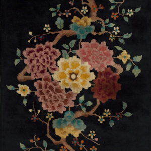 Black rug featuring a high-pile, colorful botanical design with pink, yellow, and teal flowering branches.