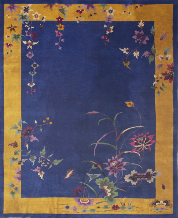 A deep blue rug features a wide gold border and stylized floral vines in purple, pink, and green.