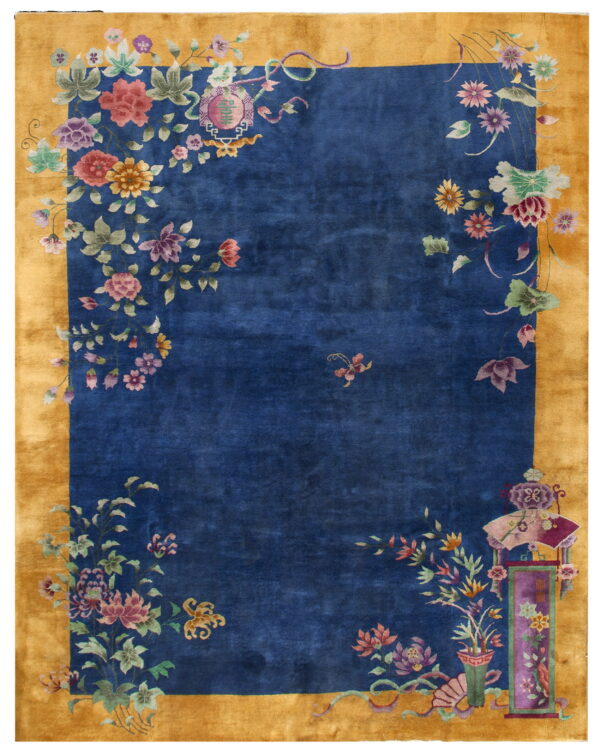A royal blue rug with a wide gold border features multi-colored botanical motifs concentrated in the corners.