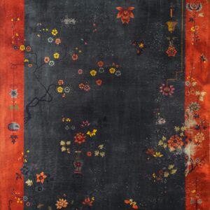 Corner of a deep red low-pile rug with natural fringe rests on rustic wood flooring near an inventory tag.