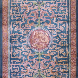 An intricate traditional rug in deep teal, salmon, and mauve with dragons and geometric fretwork.
