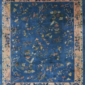 Deep blue rug with scattered flowers and butterflies, framed by a wide peach pink border.
