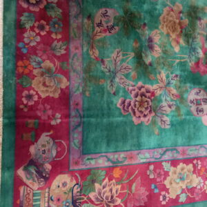 Teal high-pile rug with pink, gold, and purple flowers framed by a wide magenta border featuring vases and symbols.