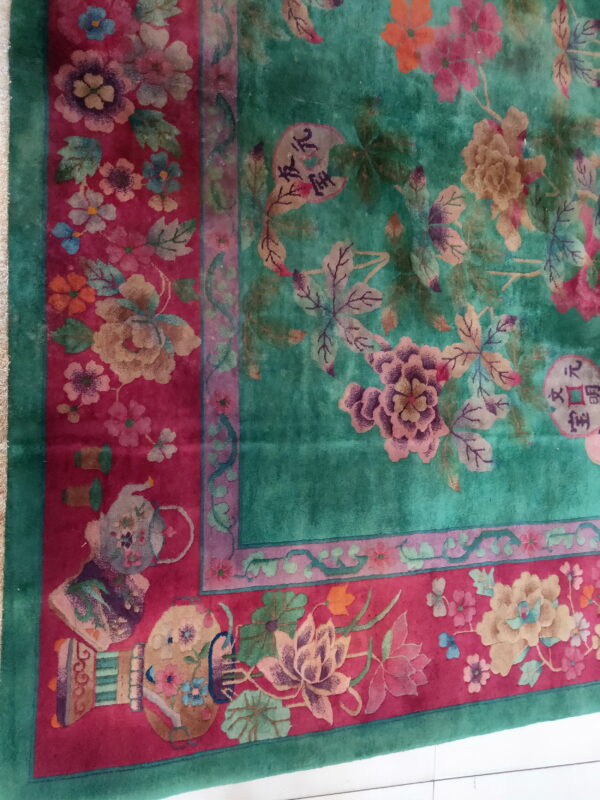 Teal high-pile rug with pink, gold, and purple flowers framed by a wide magenta border featuring vases and symbols.