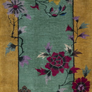 Gold border rug with a teal panel featuring large magenta, purple, and yellow floral designs.