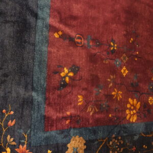 Plush burgundy field rug with delicate golden florals bordering a dark navy and teal edge.